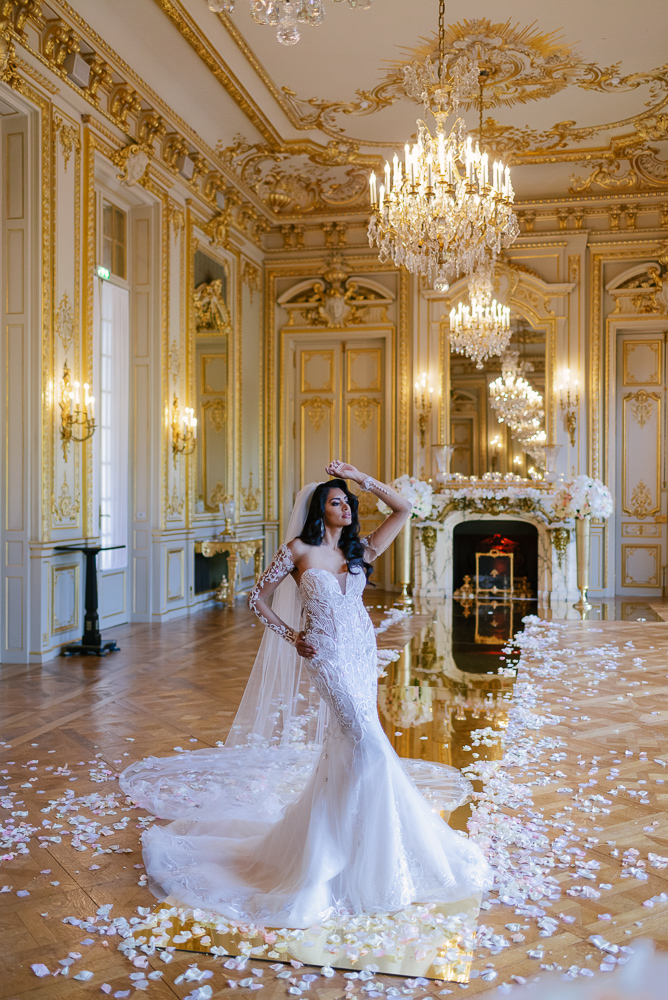 Bride posing for wedding photos in a ballroom with golden details - captured by Fran Boloni founder of The Now Time