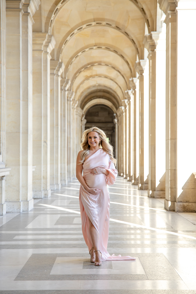 Blonde woman in pink dress posing for maternity pictures
