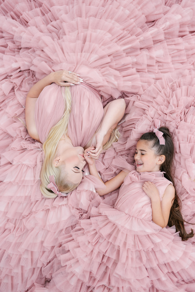 Mother and daughter posing for creative family photo on pink tulle dresses