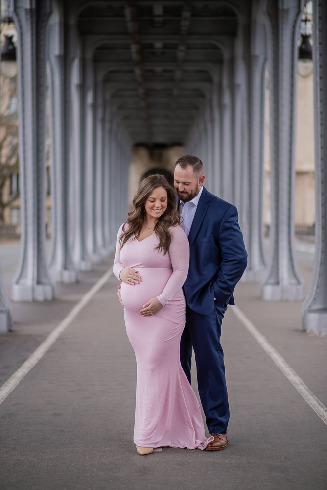 Woman in pink dress posing for maternity photos with her husband