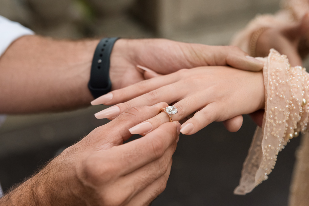 Man sliding engagement ring on fiancées finger