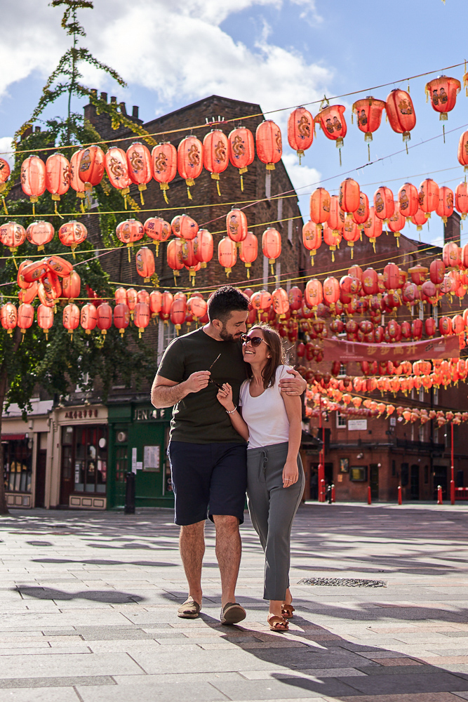Newly engaged couple walking under red lampions in China Town London