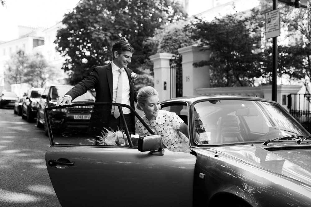 Couple jumping into a vintage Porsche on their elopement day in London
