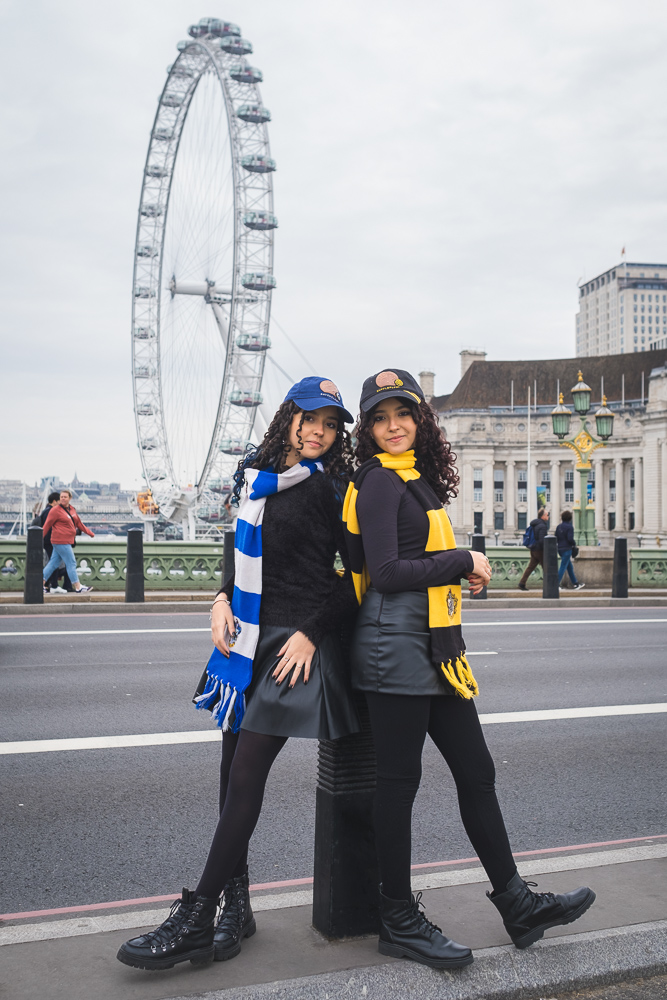sisters posing close by the London Eye with Happy Potter accessories