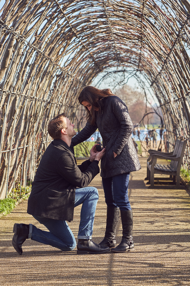 Man on his knee proposing to his girlfriend in Kensington gardens in winter
