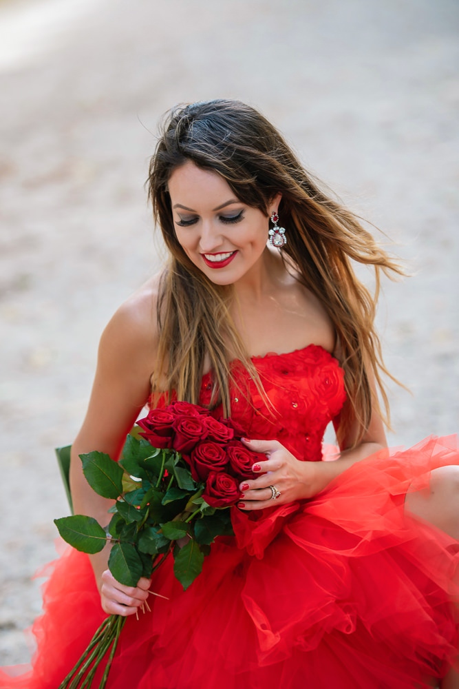 Portrait of a beautiful woman dressed in red and holding red roses in her hands