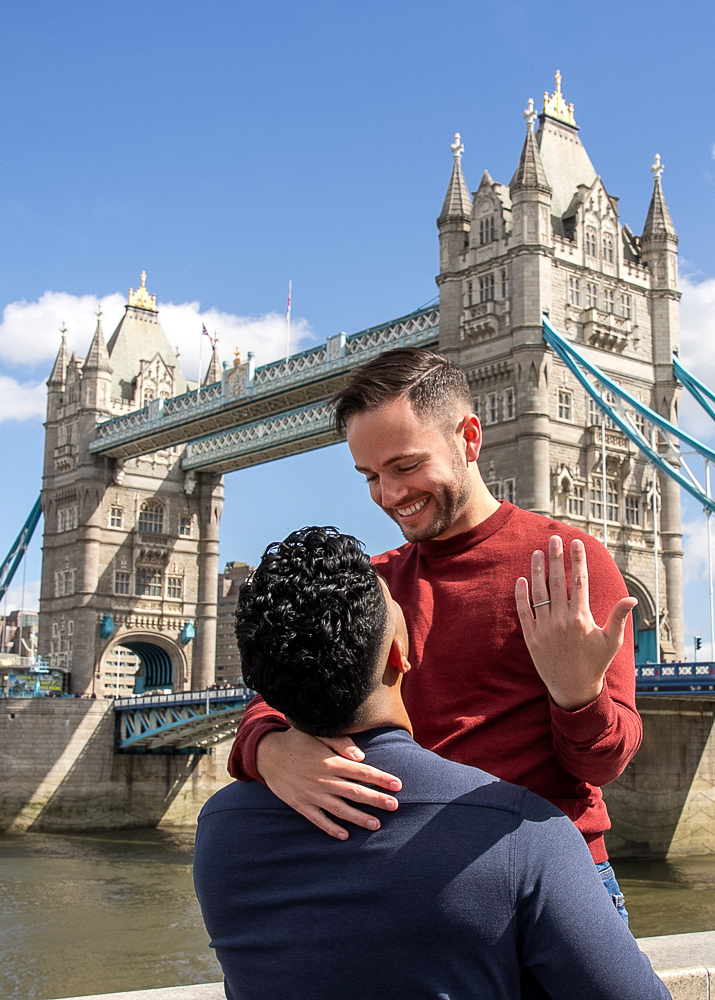 Same gender couple posing for engagement photos in front of the Tower Bridge after their marriage proposal