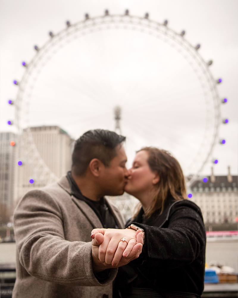 Young couple kissing in the rain on the day of their engagement at the London Eye