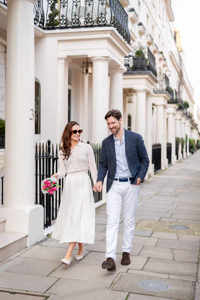 Couple dressed elegantly walk hand in hand in the streets of London on the day of their engagement