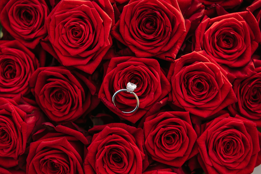 Engagement ring on top of red roses