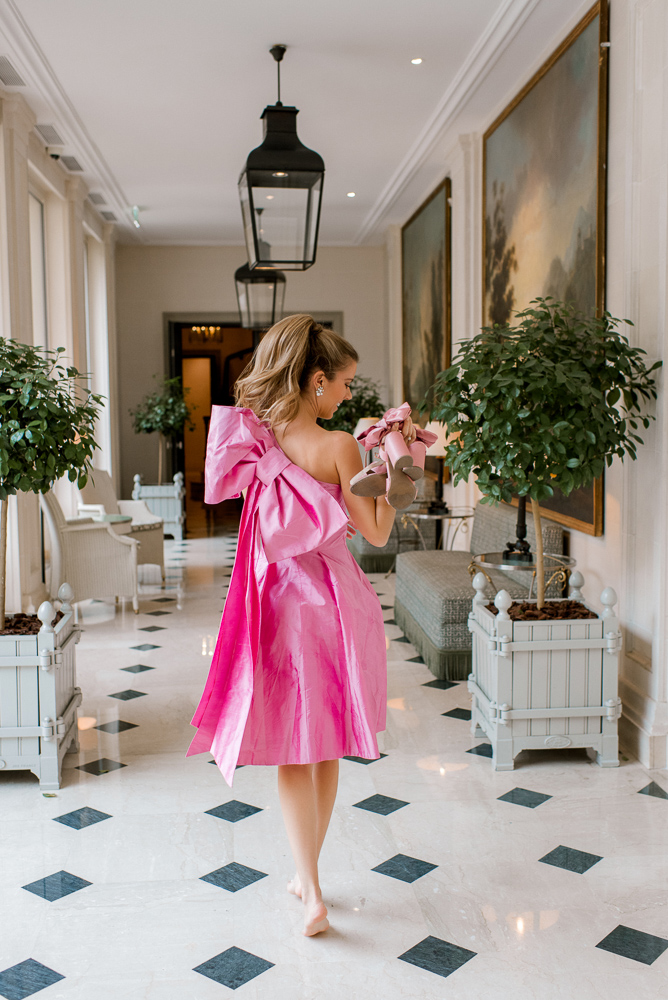 Woman in gorgeous pink dress walking with shoes in her hands