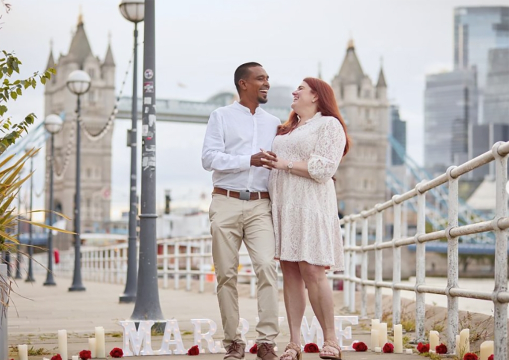 Couple posing for engagement photos and laughing during engagement photo shoot after marriage proposal