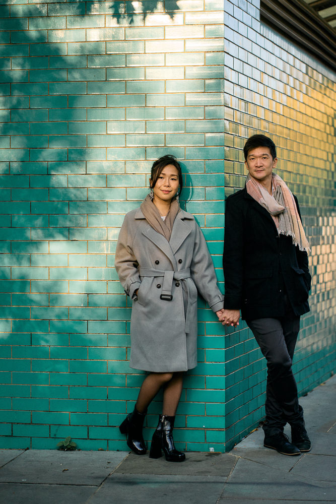 Couple posing for romantic photos against a green wall in London