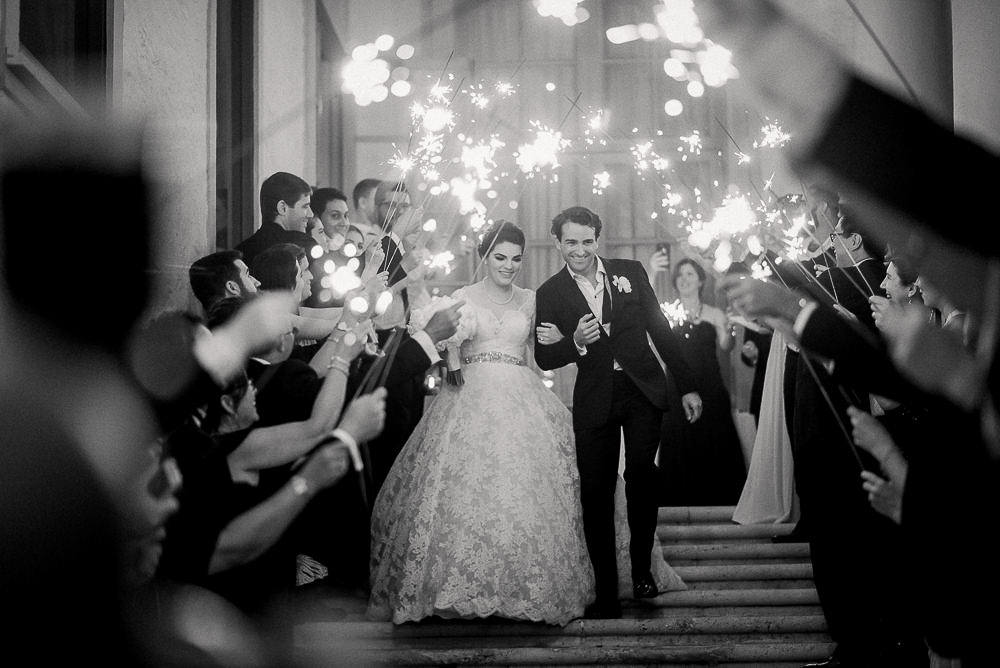 The photographer of your lifetime - Miami Wedding - Couple leaving the wedding venue surrounded by guests holding up sparklers