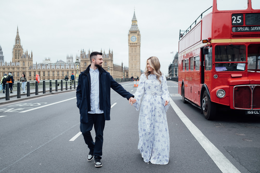 Couples photography on Westminster Bridge with double-decker red bus in London